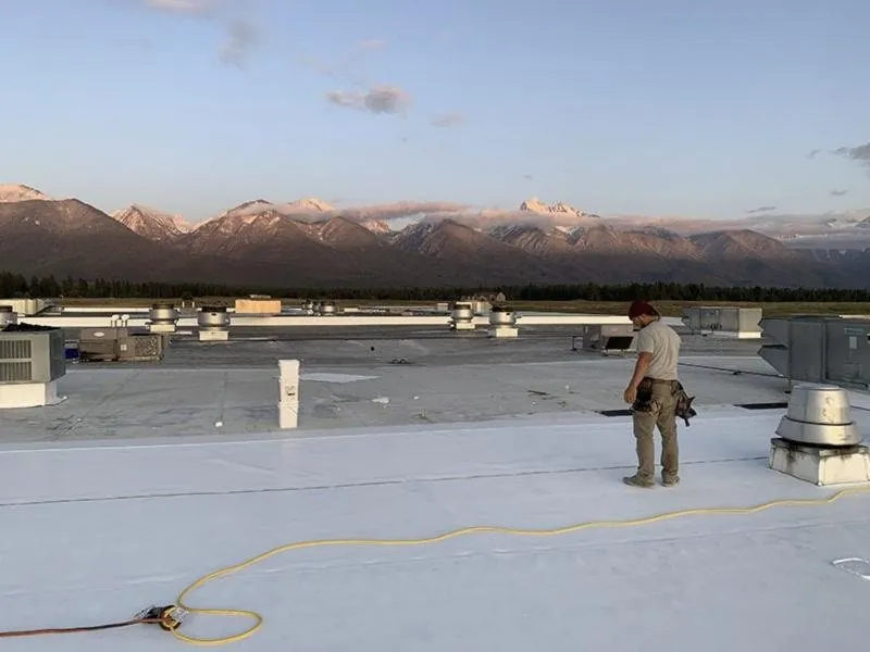 High Country Roofing crew member on a finished commercial roof at sunrise